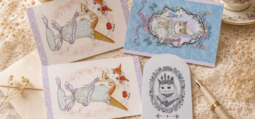 TEAPURR postcards on a cream lace table with tea, including Melt for You and garden cat cards